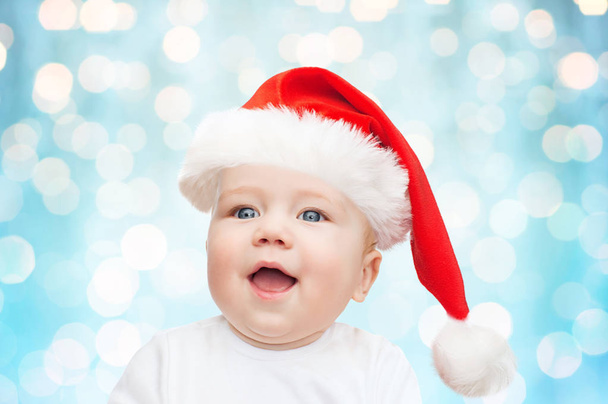 baby boy in christmas santa hat over blue lights - Фото, изображение