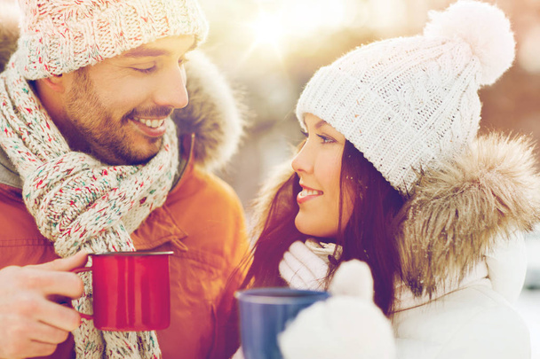 happy couple with tea cups over winter landscape - Foto, afbeelding