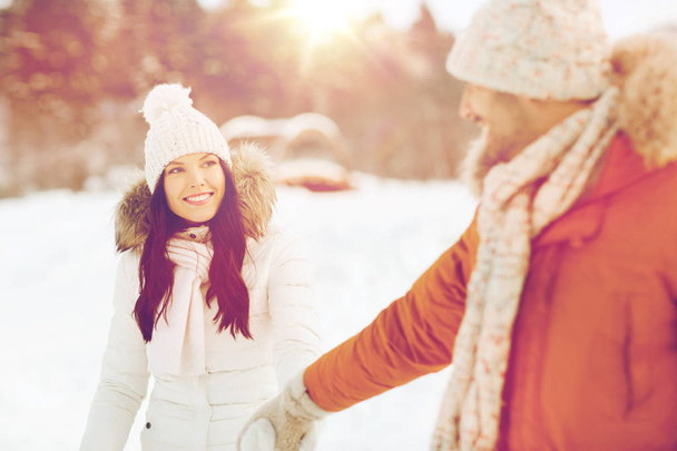 happy couple walking along snowy winter field - Фото, зображення