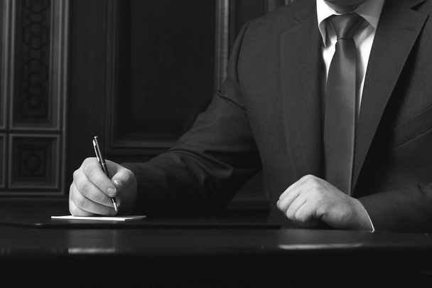 Masada oturan ve belge, siyah ve beyaz fotoğraf imzalama işadamı yakın çekim - Fotoğraf, Görsel