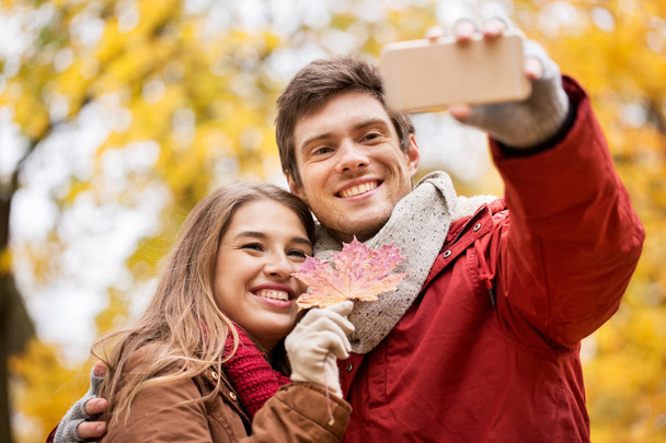 couple taking selfie by smartphone in autumn park - Zdjęcie, obraz