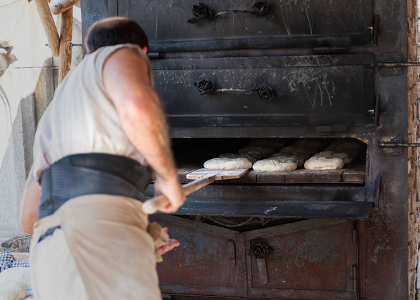 boulanger artisanal introduisant le produit dans un four à bois
 - Photo, image