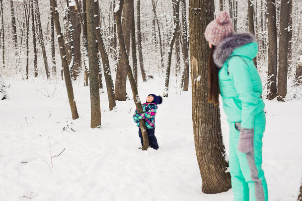Anya és a kisgyermek kislány, séta a téli erdő és birtoklás móka a hóban. Téli család. Karácsonyi és életmód fogalma. - Fotó, kép