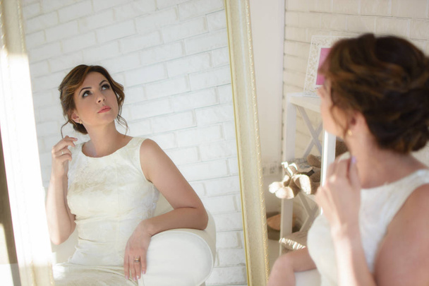 hermosa chica con el pelo oscuro en un vestido blanco y habitación luminosa
 - Foto, Imagen
