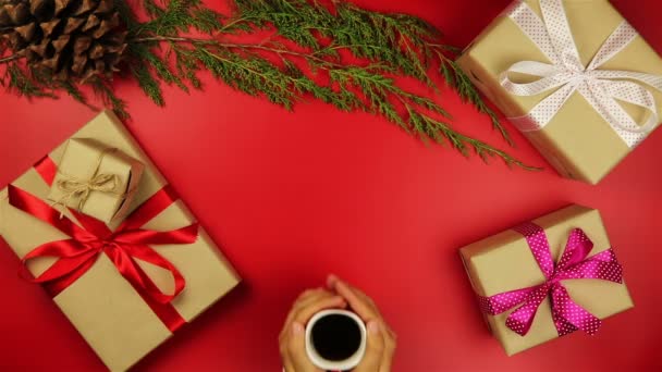 Felülnézet kezek karácsonyi ajándékokat tábla piros háttér a fenti kávé, tea. - Felvétel, videó