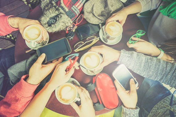 Freundeskreis trinkt Cappuccino im Café-Restaurant - Smartphone in der Hand - Technologiekonzept mit süchtigen Männern und Frauen - Lomo-Vintage-Filter mit Heiligenschein - Foto, Bild