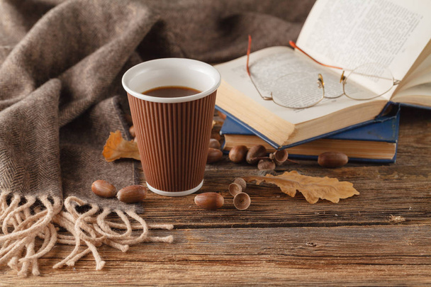 Cup of tea with old book, autumn leaves on wooden table - Fotó, kép