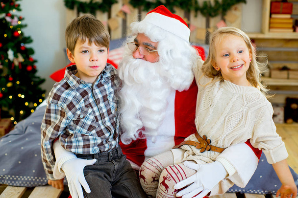 Santa Claus and two children sitting on the bed - Foto, imagen
