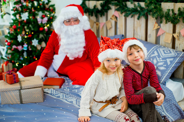 Santa Claus and two children sitting on the bed - Photo, Image