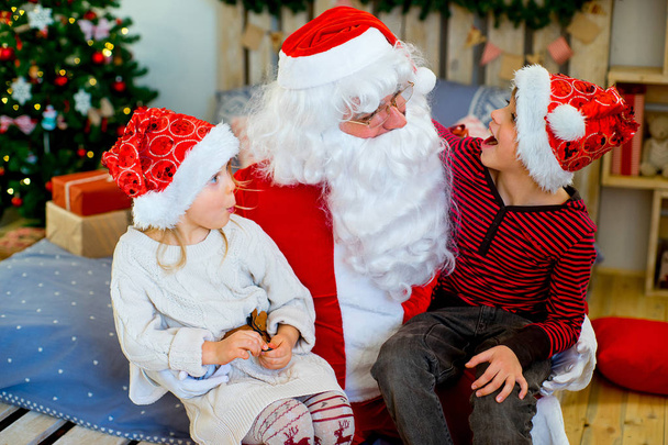 Santa Claus and two children sitting on the bed - Foto, Imagen
