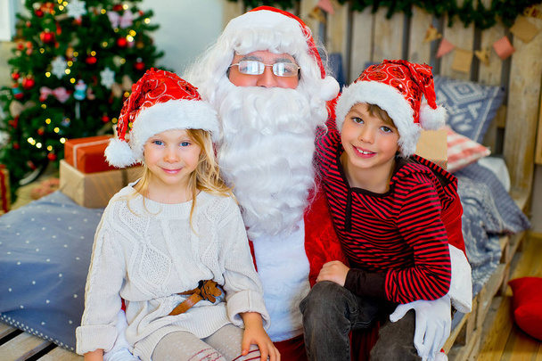 Santa Claus and two children sitting on the bed - Фото, зображення