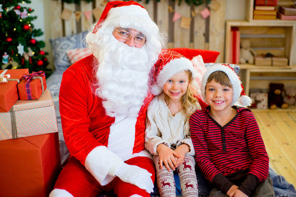 Santa Claus and two children sitting on the bed - Foto, afbeelding