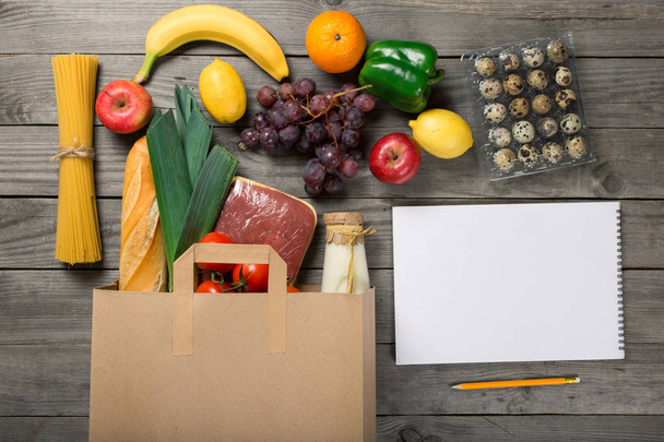 Paper bag of food products and notebook with blank page - Foto, immagini