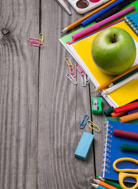 Шкільне приладдя з зеленим яблуком на дерев'яному столі
 - Фото, зображення
