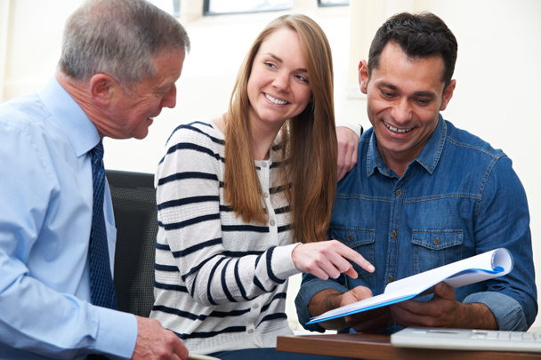 Couple With Financial Advisor Studying Document In Office - Photo, Image