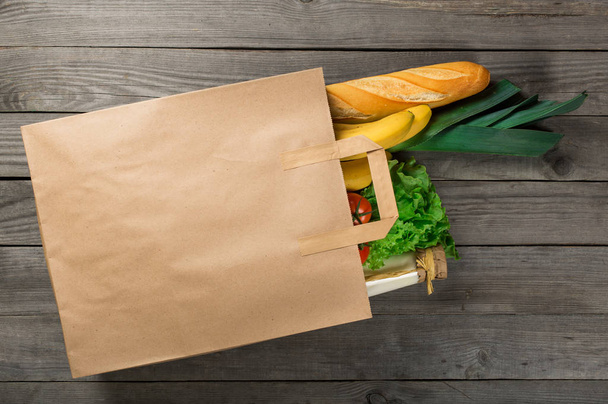 Food in paper bag on wooden background - Photo, Image