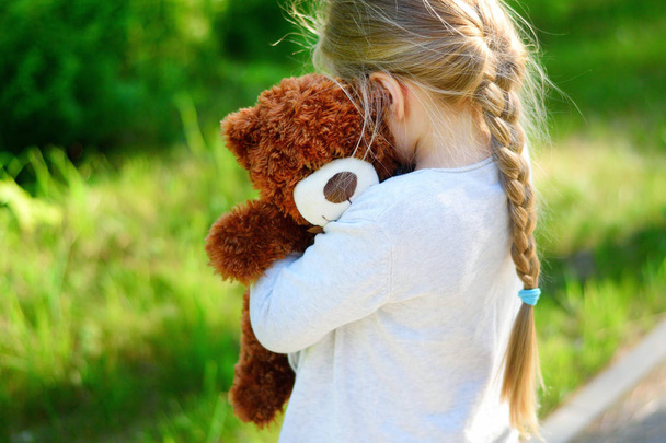Adorable sad girl with teddy bear in park. - Photo, Image