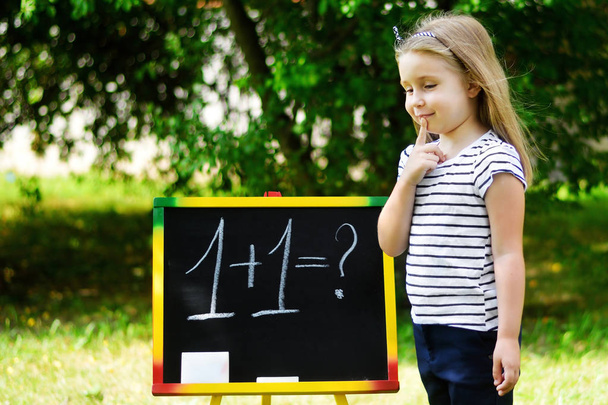 Adorable funny little girl at blackboard practicing counting and math - Photo, Image