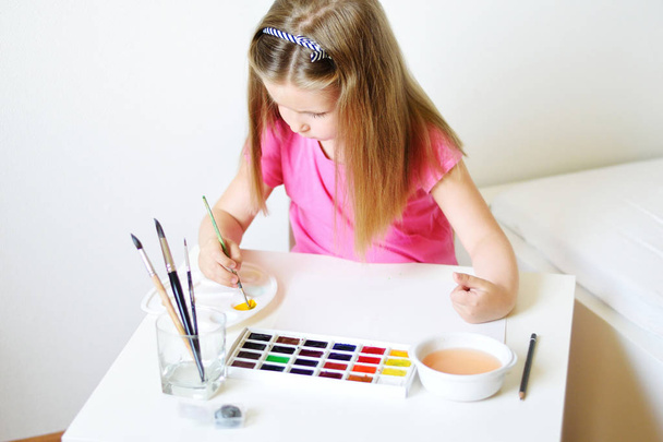 Adorable chica de pintura con acuarela en una habitación blanca soleada en
  - Foto, Imagen