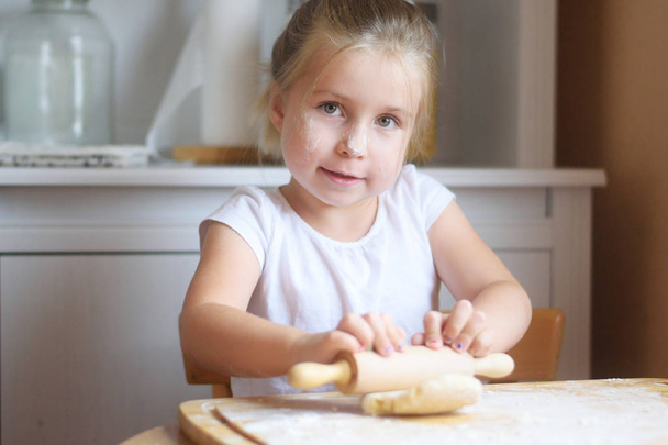 Красивая маленькая девочка делает тесто для макарон
 - Фото, изображение
