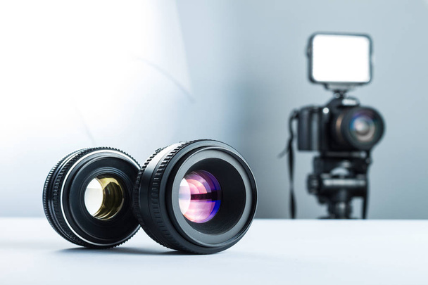 Two lenses on a white table in stuidio, against the background of the DSLR camera to light and softbox. - Fotó, kép