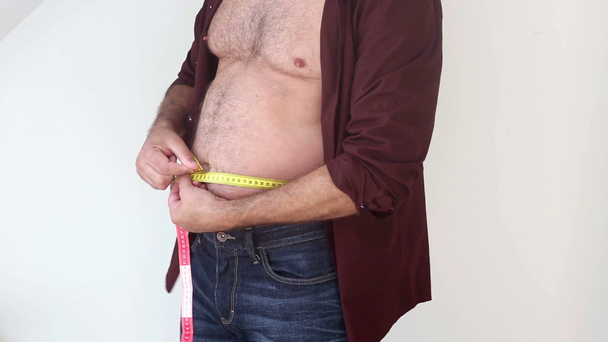 primer plano del hombre midiendo su vientre gordo y tratando de mirar flaco
 - Metraje, vídeo