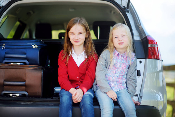 Dos adorables niñitos sentados en un coche antes de irse de vacaciones con sus padres
 - Foto, imagen