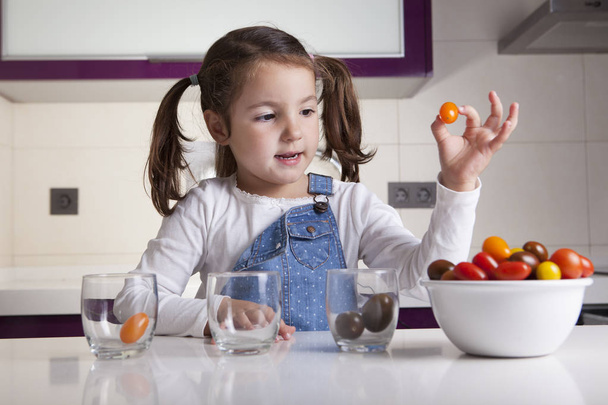 Mała dziewczynka sortowanie według kolorów pomidorkami - Zdjęcie, obraz