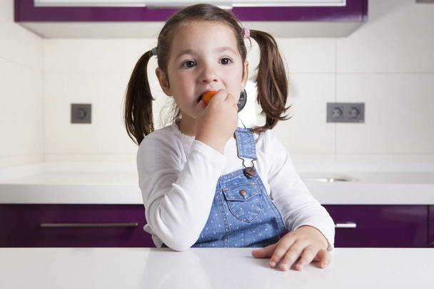 Pieni tyttö maistaa raaka värikäs kirsikka tomaatti
 - Valokuva, kuva