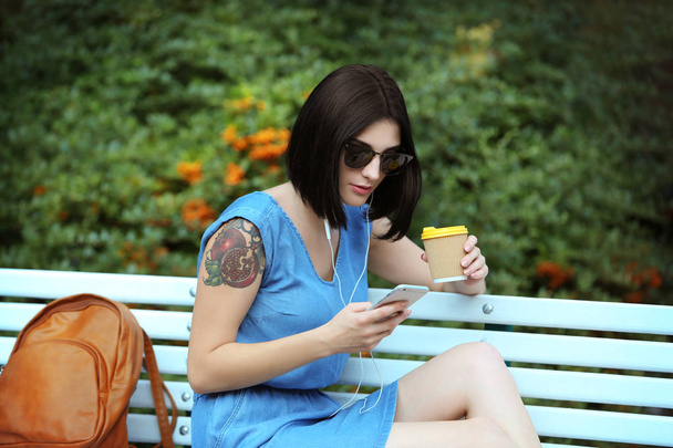 Young beautiful  girl  outdoors with phone and  cup of coffee - Foto, Imagem