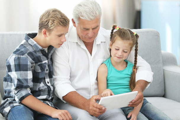 Grandfather and grandchildren with tablet on couch - Photo, image