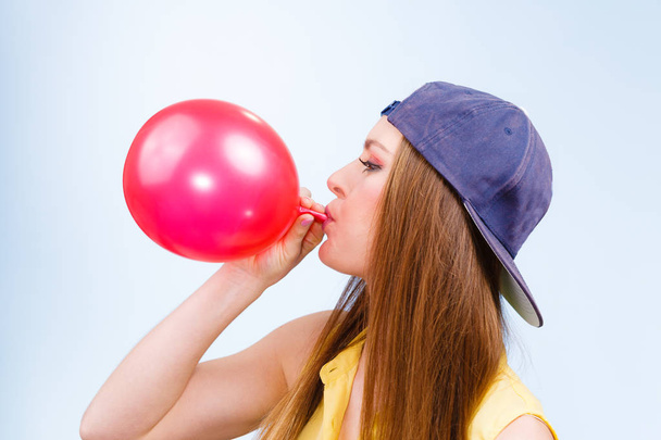 Female teenager inflating red balloon. - Fotografie, Obrázek