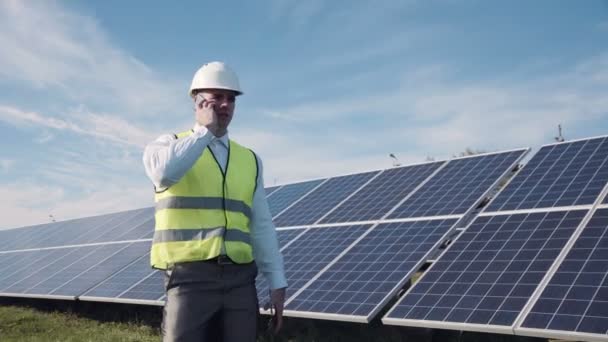 Homem andando perto de painéis solares falar por telefone
 - Filmagem, Vídeo