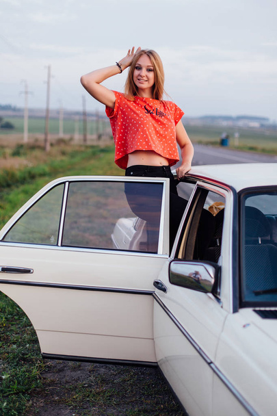 Portret pięknej, młodej kobiety, stojący w pobliżu retro samochodów - Zdjęcie, obraz