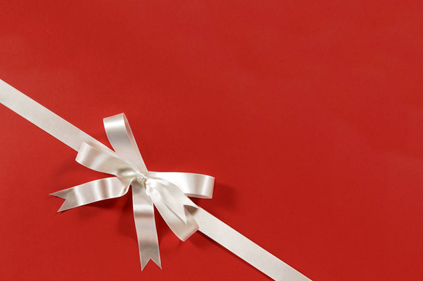White gift bow ribbon red paper background corner diagonal - Valokuva, kuva