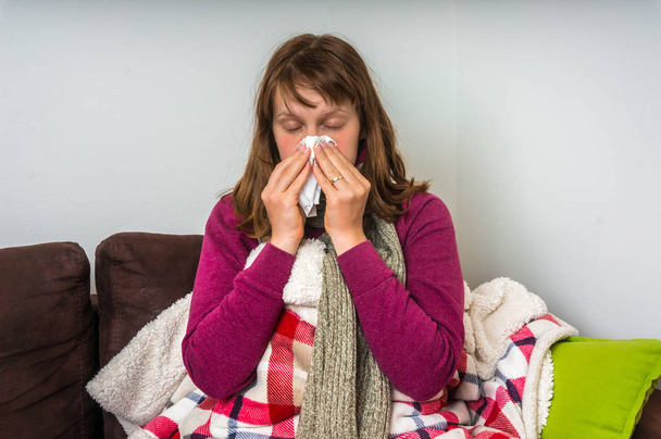 Mujer enferma teniendo gripe y sonándose la secreción nasal
 - Foto, Imagen