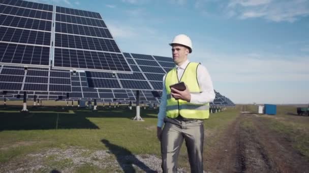 Muž v vesta pěší poblíž solární panely - Záběry, video