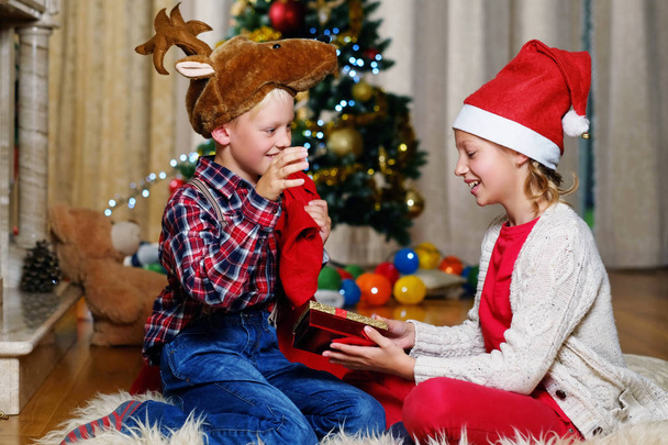 Junge mit Weihnachtsmütze und Mädchen mit Geschenk - Foto, Bild