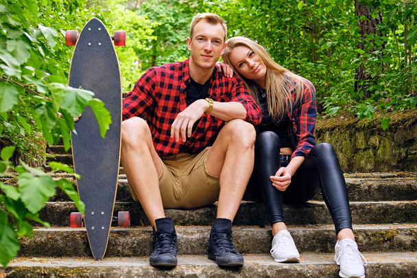 Couple relaxing on the steps after longboard ride. - Photo, Image