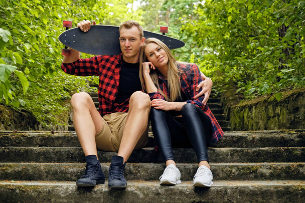 Couple relaxing on the steps after longboard ride. - Photo, Image
