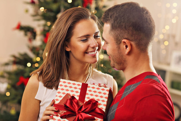  couple with present over Christmas tree - Фото, зображення