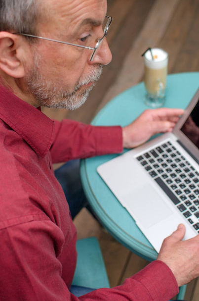 Aged man using his laptop - Foto, afbeelding