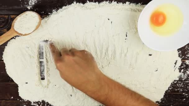 平面図若い男が上から木製の机に白い粉の単語小麦粉を書き込みます. - 映像、動画