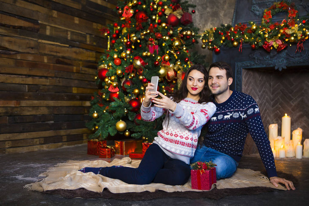 クリスマスを祝う暖炉近く若いカップル - 写真・画像