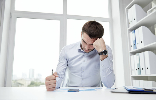 stressed businessman with papers in office - Zdjęcie, obraz