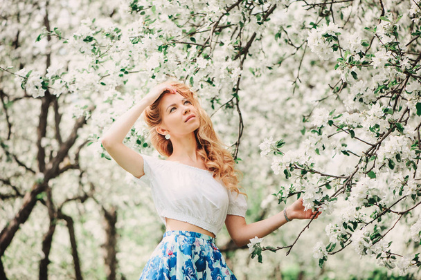 beautiful young woman in floral maxi skirt walking in spring - Foto, Imagem