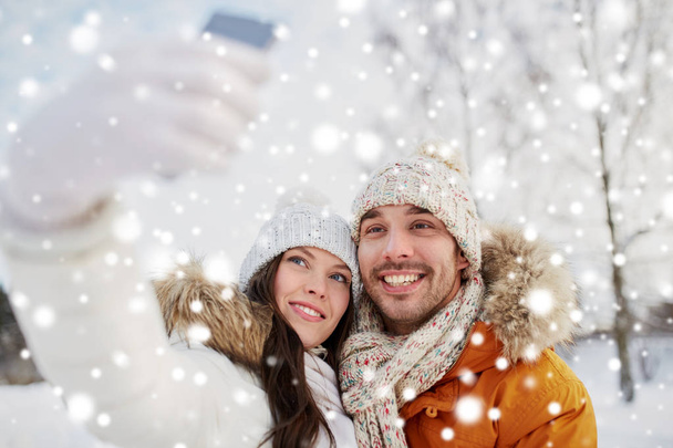 happy couple taking selfie by smartphone in winter - Foto, Imagen