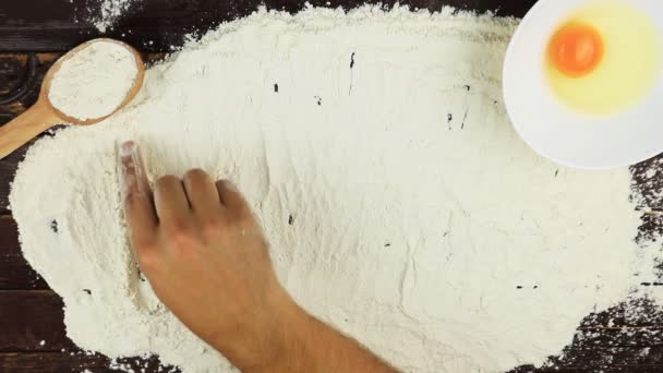 Top view Young man writes a word pastry on white flour at wooden desk from above. - Footage, Video