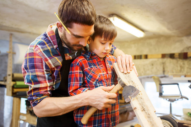 father and son with ax and wood plank at workshop - Foto, imagen