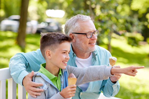 old man and boy eating ice cream at summer park - Фото, зображення